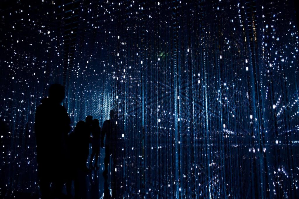 A group of people silhouetted against a blue, starry background which suggests they are within the inner workings of a piece of technology